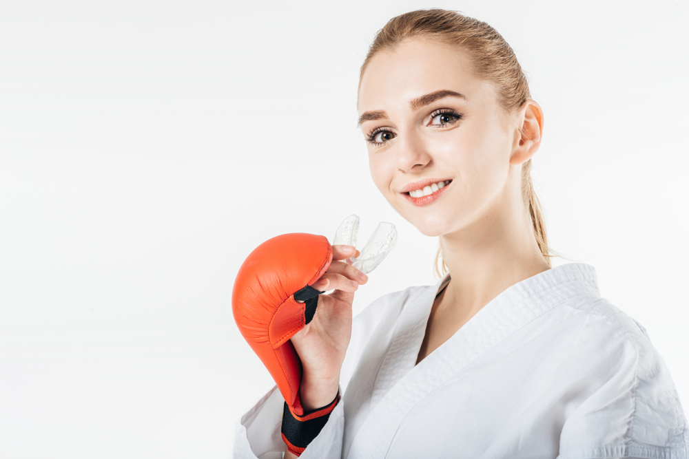 Smiling,Female,Karate,Fighter,Holding,Mouthguard,Isolated,On,White a young boxer is happy with the protection from her custom mouthguards